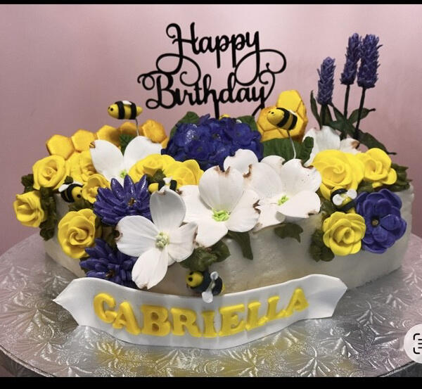 Custom birthday cake featuring handcrafted sugar flowers, bees, lavender, and personalized fondant details.
