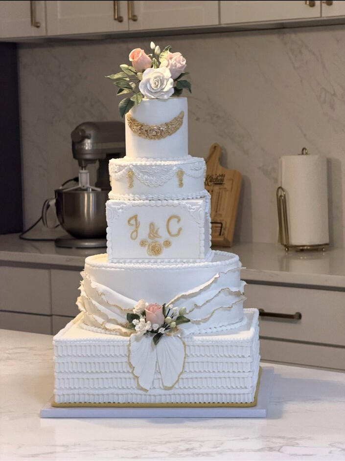 Luxury Custom Wedding Cake Five-tier luxury white wedding cake with handcrafted ruffles, pearl and champagne-gold details, and pink and white floral accents